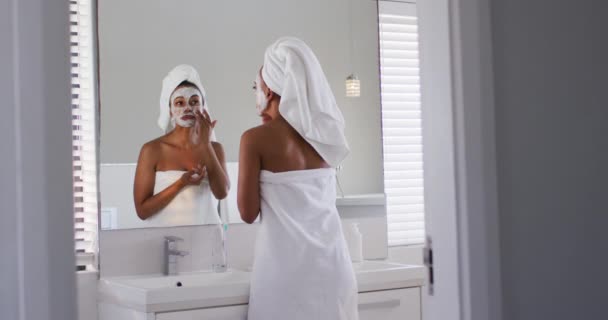 Afričanky americká žena použití obličejová maska, zatímco v zrcadle v koupelně — Stock video