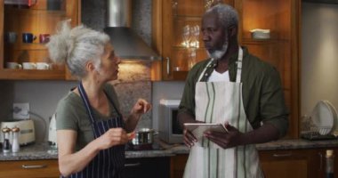 Kafkas kıdemli kadın önlük giyip evdeki mutfakta kocasına doğranmış sebze yediriyor.