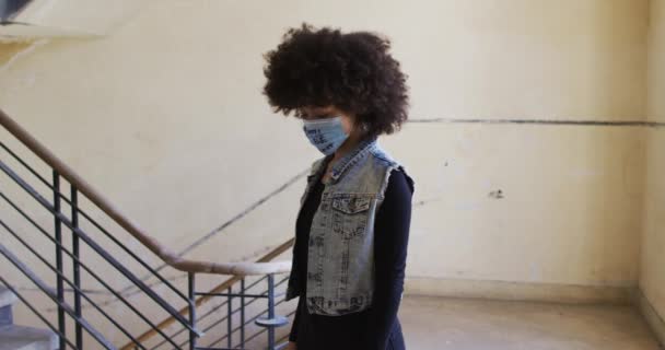 Retrato de mulher afro-americana usando máscara facial de protesto ao pé das escadas — Vídeo de Stock