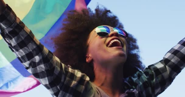 Güneş gözlüğü takan Afrikalı Amerikalı kadın. Havada bayrak sallıyor. — Stok video
