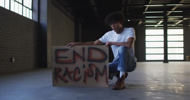 Boş otoparkta protesto pankartı tutan Afro-Amerikan bir adamın portresi. — Stok video