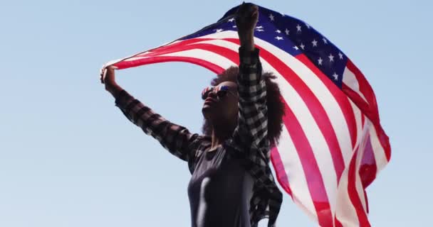 Femme afro-américaine portant des lunettes de soleil tenant le drapeau américain dans les airs — Video