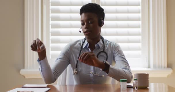 Porträt einer afrikanisch-amerikanischen Ärztin, die während eines Videogesprächs Notizen macht — Stockvideo