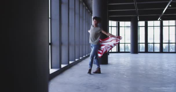 Африканський американець танцює, тримаючи прапор Америки в порожньому гаражі. — стокове відео