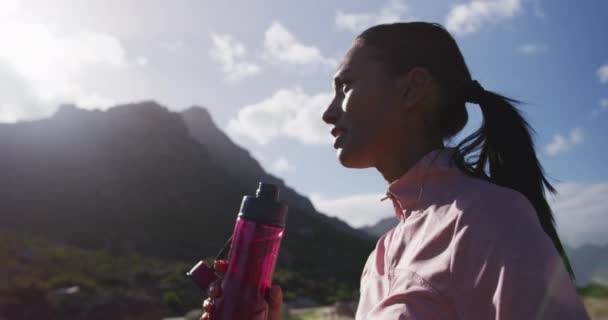 Afroamerykanka pijąca wodę z butelki podczas wędrówki w górach — Wideo stockowe