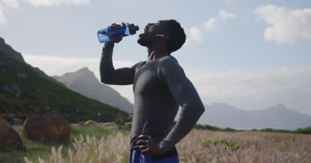 Африканський американець під час прогулянок по горах п "є воду з пляшки. — стокове відео