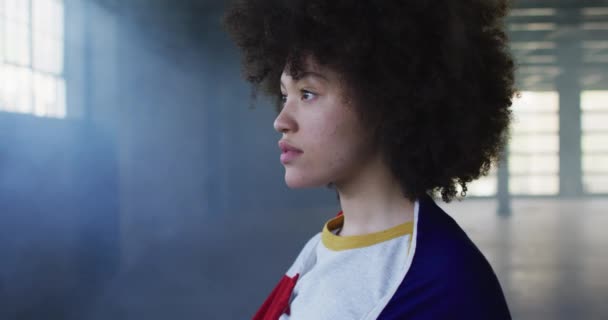 Retrato de mulher afro-americana com bandeira americana nas costas em garagem vazia — Vídeo de Stock