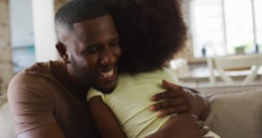 Afrikalı Amerikalı kız ve babası kanepede gülümseyip sarılıyorlar. Karantina süresince evde tek başına kalarak eğleniyor..