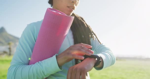 Africano americano mulher em sportswear segurando tapete usando smartwatch no parque — Vídeo de Stock