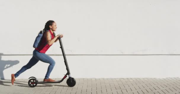 Afričanky americká žena nosí batoh na koni skútr na promenádě u moře — Stock video