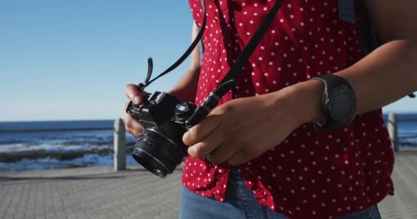 Afrykańska amerykanka stojąca i trzymająca kamerę na promenadzie nad morzem — Wideo stockowe