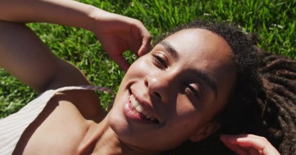 Primo piano di donna afro-americana sdraiata sull'erba e sorridente nel parco — Video Stock