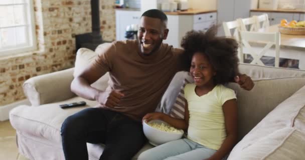 Afrikai Amerikai Lány Apja Kanapén Popcornt Esznek Tévénézés Pacsizás Közben — Stock videók