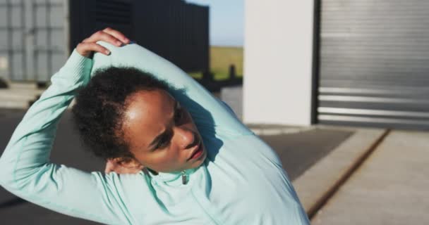 Afroamerykanka w odzieży sportowej rozciągająca się na ulicy przed treningiem — Wideo stockowe