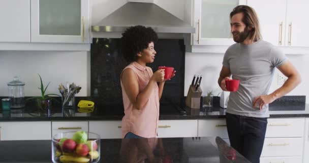 自宅のキッチンでコーヒーカップを持っている混合レースカップル 隔離されたまま家にいると — ストック動画