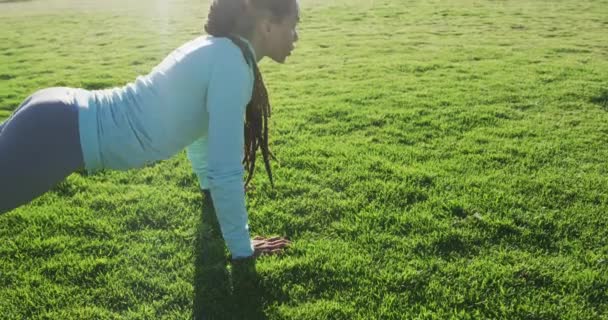 African american woman in sportswear doing press ups in park — Stock Video