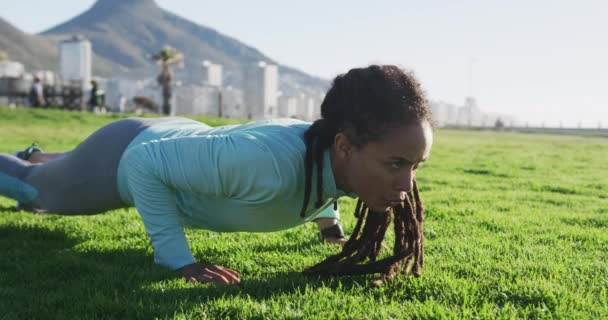 Mujer afroamericana en ropa deportiva haciendo flexiones de prensa en el parque — Vídeos de Stock