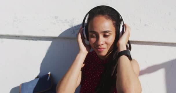 Afrika kökenli Amerikalı kadın kulaklık takıyor ve deniz kenarında müzik dinliyor. — Stok video