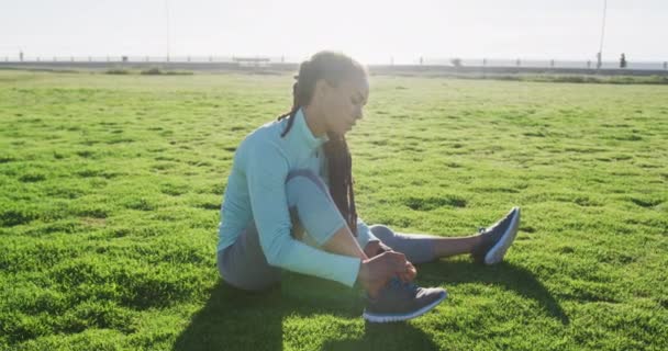 Afroamerykanka w odzieży sportowej zawiązuje sznurówki w parku — Wideo stockowe