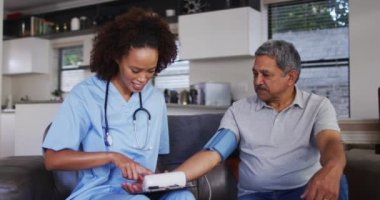 Üst düzey melez adam ve bayan doktor kan basıncını ölçmek için eve geliyorlar.