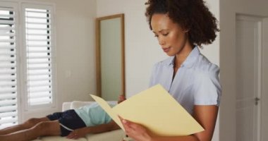 Kamera karşısında elinde defter ve yazı tutan melez kadın fizyoterapistin portresi.