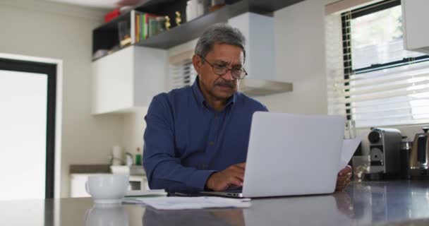 Üst düzey melez adam mutfakta dizüstü bilgisayar kullanıyor. — Stok video