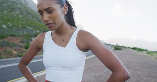 Mujer afroamericana usando ropa deportiva tomando un descanso de correr en el camino — Vídeos de Stock