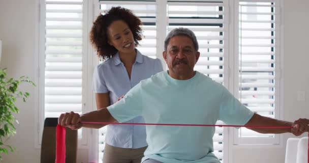 混合型女理疗师运用运动带帮助老年人运动 — 图库视频影像