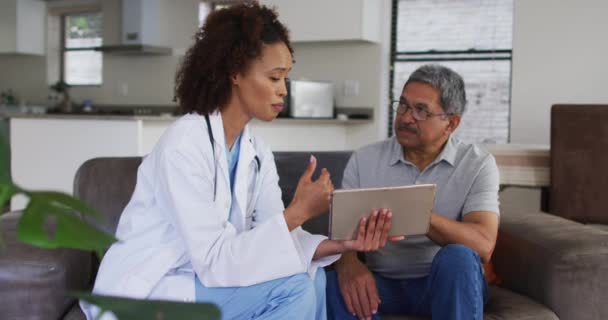 Médico femenino de raza mixta y hombre mayor usando tableta y hablando — Vídeos de Stock