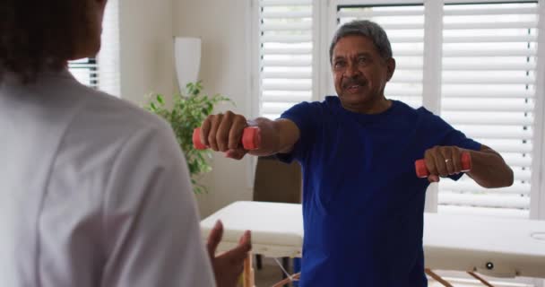 混合型女理疗师帮助老年人使用哑铃进行运动 — 图库视频影像