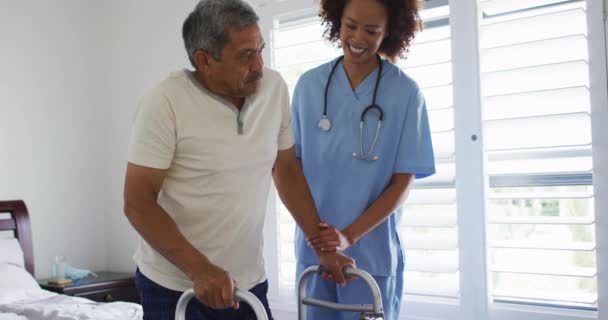 Médico de raza mixta visitando casa ayudando a paciente mayor a levantarse — Vídeos de Stock