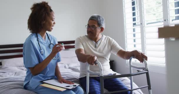 Senior mixed race man with female doctor talking and holding pills — Stockvideo