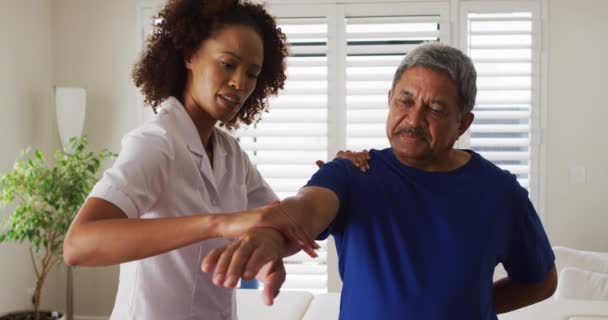 Physiothérapeute féminine de race mixte aidant l'homme âgé étirant son bras — Video