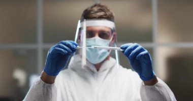 Koruyucu giysiler ve yüz kalkanı takan beyaz erkek sağlık görevlisi laboratuvarda DNA testi yapıyor. Coronavirus covid 19 salgını sırasında sağlık, tıbbi araştırma teknolojisi ve hijyen..