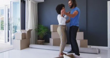 Yeni apartman dairesindeki karton kutuların arasında dans eden melez bir çift. Taşınma ve emlak konsepti