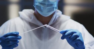 Koruyucu giysiler ve yüz maskesi takan bir tıp çalışanı hasta örnekleme testi yapıyor. Coronavirus covid 19 salgını sırasında sağlık, tıbbi araştırma teknolojisi ve hijyen..