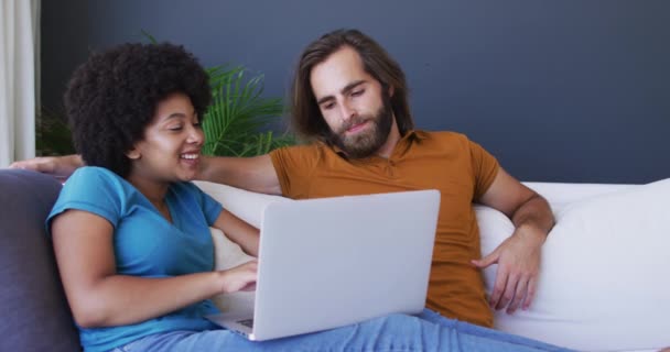 Couple Mixte Assis Sur Canapé Utilisant Ordinateur Portable Dans Salon — Video