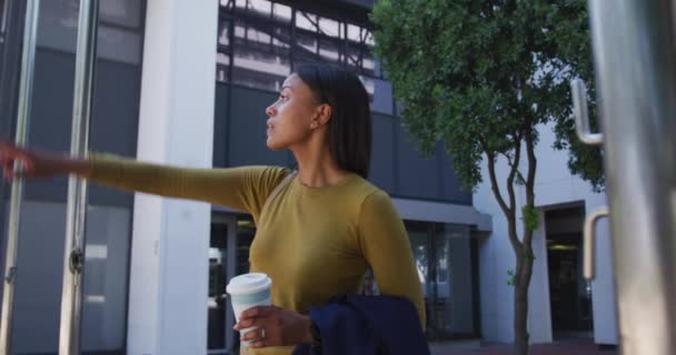 街上的非裔美国妇女拿着咖啡 举手叫停出租车 城市里到处都是专业的商业人士 — 图库视频影像