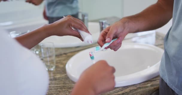 混合种族夫妇在浴室的刷子上涂牙膏的中间部分 在隔离隔离状态下待在家里 — 图库视频影像