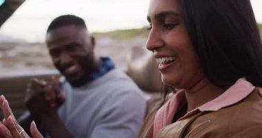 Afro-Amerikalı çift üstü açık arabada otururken birbirlerine sarılıyorlar. Yolculuk ve macera konsepti