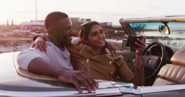 Üstü açık arabada otururken özçekim yapan Afrikalı Amerikalı çift. Yolculuk ve macera konsepti