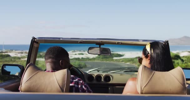 道路上のコンバーチブル車に座っている間 アフリカ系アメリカ人のカップルは空中で腕を上げています 旅と冒険のコンセプト — ストック動画
