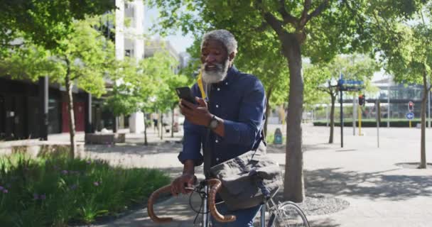 Африканский Пожилой Человек Велосипедом Использующий Смартфон Дороге Гигиена Социальное Дистанцирование — стоковое видео
