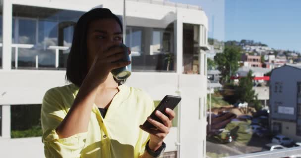混血种族的人喝着一杯咖啡 在屋顶平台上使用智能手机 隔离检疫期间单独呆在家里 — 图库视频影像