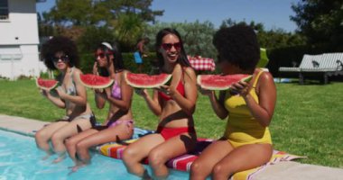 Havuz başında oturup karpuz yiyen çeşitli kadın arkadaşlar. Yazın dışarıda takılır ve dinlenir..