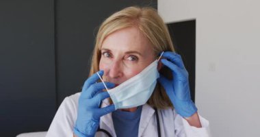 Kafkas kıdemli kadın doktor ameliyat eldiveni takıyor ve maske takıyor. Coronavirüs covid 19 salgını sırasında sağlık hizmetleri koruması.