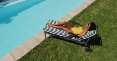 Güneşlenme havuzunda güneşlenen melez ırktan bir kadın. Yazın dışarıda takılıp dinleniyorum..