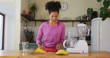 Evdeki mutfakta meyve suyu yapmak için meyve doğrayan melez bir kadın. Karantina karantinasında tek başına evde kalmak