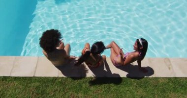 Havuz başında oturan çeşitli bayan arkadaş grupları. Yazın dışarıda takılıp dinleniyorum..