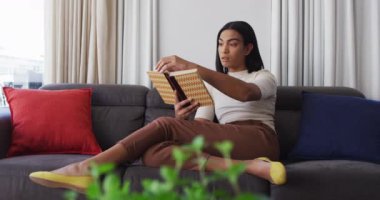 Karışık cinsiyet değişkenleri koltukta oturup evde kitap okuyor. Karantina süresince evde tecrit altında kalmak.